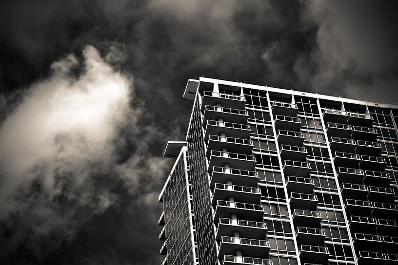 Schwarz Weiß Bild von einem Hochhaus  vor einem Wolkenhimmel