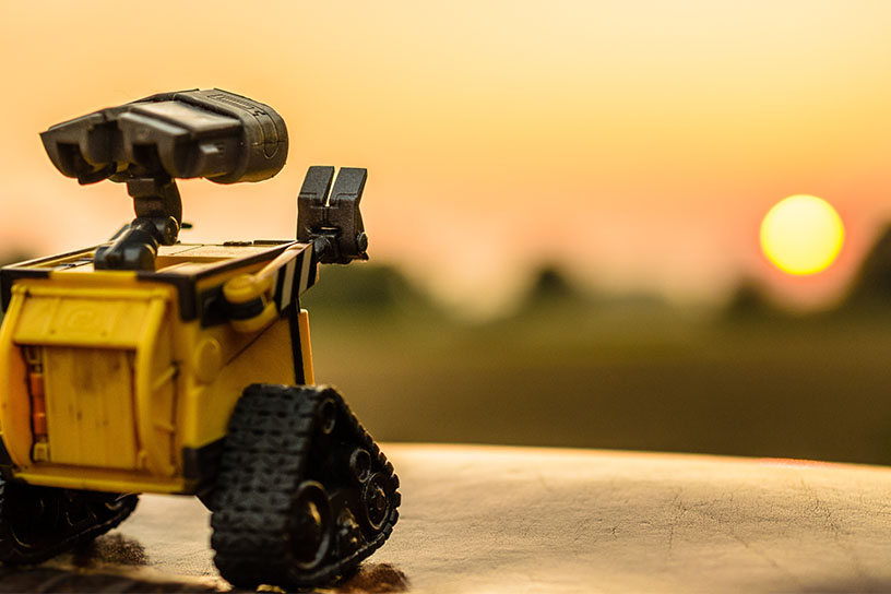 Der Roboter Wall-E schaut in die Fehrne zu einem Sonnenuntergang.